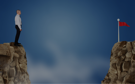 Homme en costume sur un précipice, regardant un drapeau rouge au sommet d'une autre falaise, symbolisant un objectif à atteindre.