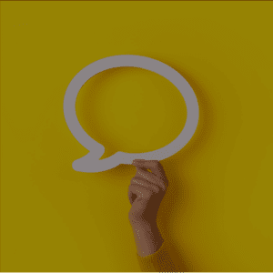 Une main tenant une bulle de dialogue blanche sur fond jaune, symbolisant la communication ou l'échange.