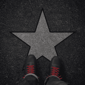 Des chaussures avec des lacets rouges sur une étoile dessinée sur le sol, créant une illusion de célébrité.