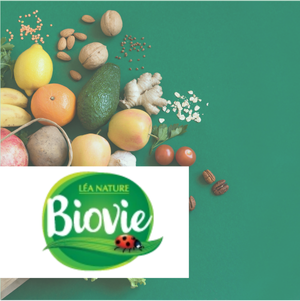 Un assortiment coloré de fruits, légumes, noix et graines sur fond vert vif, avec le logo "Léa Nature Biovie" en avant-plan.