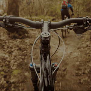 Se lancer Vue à la première personne de la conduite d'un vélo sur un sentier forestier, avec des mains sur les poignées.